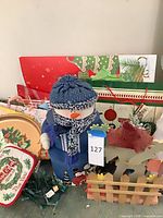 Group shot showing snowman, floral arrangement, wooden reindeer, background wrapping