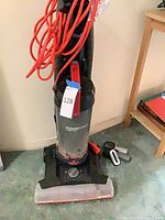 Full view of vacuum with hose and two attachments on floor