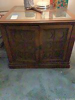 Front view of brown wood cabinet, shows two doors and glass top panes