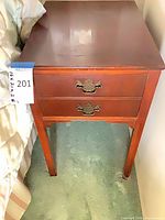 Front view of cherry veneer nightstand with two drawers and brass pulls