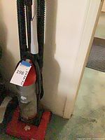 Front view of red Dirt Devil upright vacuum with clear canister and hose