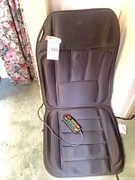 Front view of black HoMedics massage seat cushion showing seat and back panels and wired remote