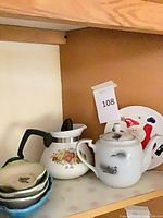 Group shot showing teapot, carafe, stacked green-rim dishes and Santa plate