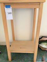 Full view of light natural wood accent table showing top, legs and lower shelf