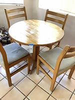 Round dining table with three of four chairs visible