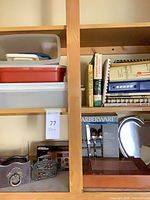 Shelf view showing boxed Farberware flatware, cookbooks, emergency radio packaging and framed plaque