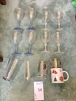 Full lot showing all 13 pieces laid out: blue-stemmed goblets, clear stemware, metallic-leaf tumblers, holiday mug