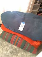 Stacked view of blue, orange and striped blankets