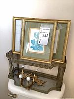 Both framed prints stacked and two brass hooks on mesh shelf