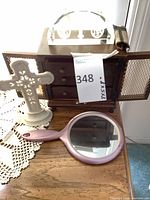 Group shot showing wood jewelry chest, ceramic cross, crystal paperweight on top, vanity mirror in front