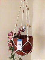 Full view of hanging macramé planter with faux orchid