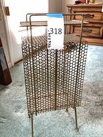 Front view of perforated metal magazine rack showing brass tone finish