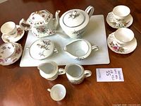 Full group view showing both teapots, creamers, sugar bowl, cups and saucers