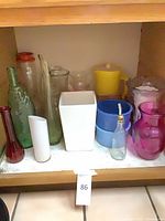 Shelf containing assorted glass, ceramic and plastic vases, planters, pitchers and bottles