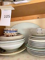 Stacked plates, bowls and glass bowl on shelf showing quantity and mix