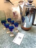 Group shot showing six cobalt blue glasses, three vases, shell rooster, and stainless carafe