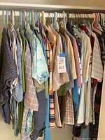 Assorted shirts hanging on closet rod showing variety of styles and patterns
