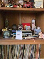 Overall view of shelf showing Greyhound bus, snow globe, picture frames, religious items, figurines, vinyl records below