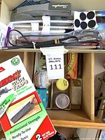Top view of drawer showing stapler, glue traps, felt pads, protractor, twine, small tins, assorted hardware