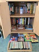 Cabinet showing shelves of CDs, VHS tapes and drawer of cassette tapes