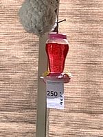 Front view of red/pink plastic hummingbird feeder hanging, lot tag visible