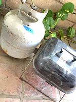 White propane cylinder and black portable grill side by side