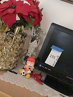 TV, vase with poinsettias, Mickey figure, shell ornament on lace mat