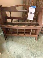 Front view of brown wooden magazine rack showing spindle dividers, scalloped rails and carry handle