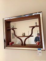 Front view of mirror showing wood frame, mirrored border, integrated shelves, ceramic figurines, red votive candles