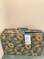 Front of floral vinyl suitcase showing exterior zipper pocket and handle