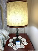 Full view of metal table lamp with shade illuminated on bedside table