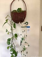 Full view of wicker planter with live plant and ceramic wind chime below