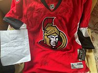 Front view of signed Ottawa Senators jersey with COA sheet and attached retail tags