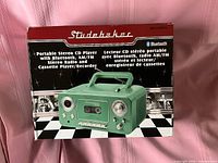 Front of retail box showing Studebaker mint green portable stereo CD player with cassette and radio