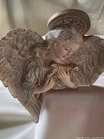 Front view of resin angel edge-sitter figurine showing wings, halo, scroll