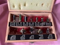 Open box displaying 11 router bits with one empty slot