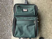 Front view of green suitcase showing two exterior zippered pockets and brand plate