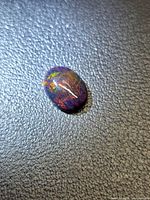 Front view of oval black opal showing play-of-color