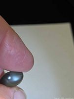 Oval cabochon star moonstone between fingers showing body color and star