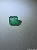 Front view of octagon-cut green emerald on neutral background