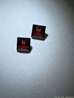 Two square red garnets on neutral background