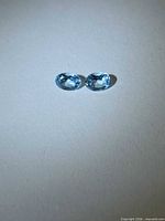 pair of oval blue topaz stones on neutral background