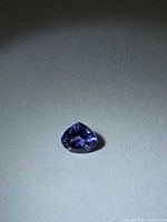 Front view of pear-cut bluish-violet tanzanite placed on neutral background