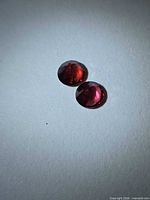 Pair of round cherry red garnets on light background