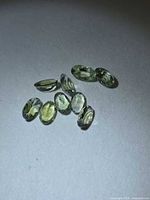 Nine oval lemon-lime tanzanite stones on grey background