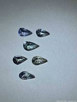 Six pear cut tanzanite gemstones displayed on white background
