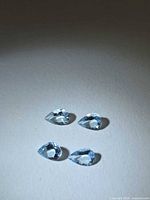 Four pear-cut aquamarine gemstones on neutral background