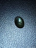 Oval cabochon green star sapphire on textured background