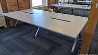 Overall view of white four-seat workstation desk, angled metal legs visible