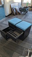 pair of black metal mobile file cabinets with blue seat cushions, drawers extended